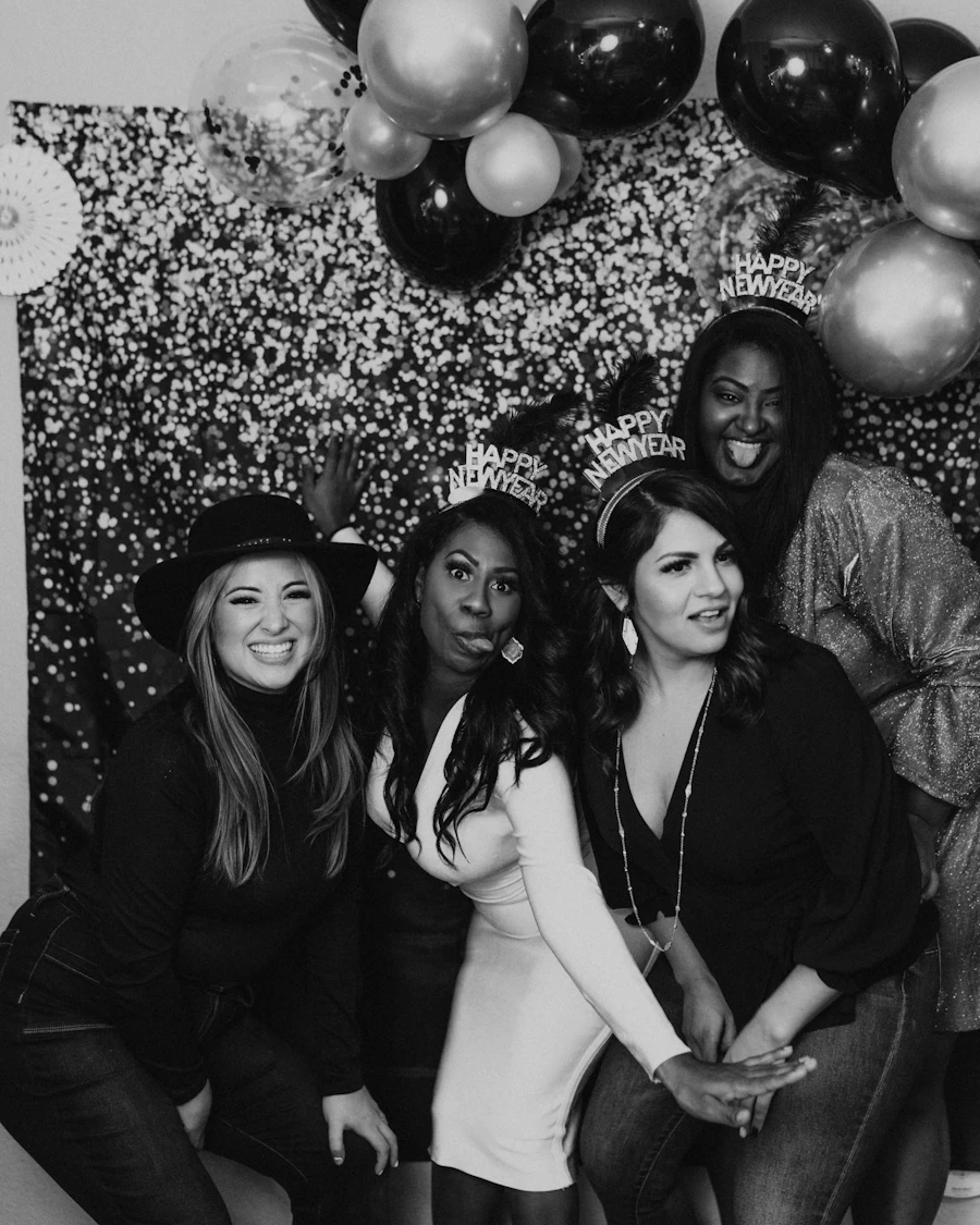 Group of friends posing in party hats in front of a balloon backdrop