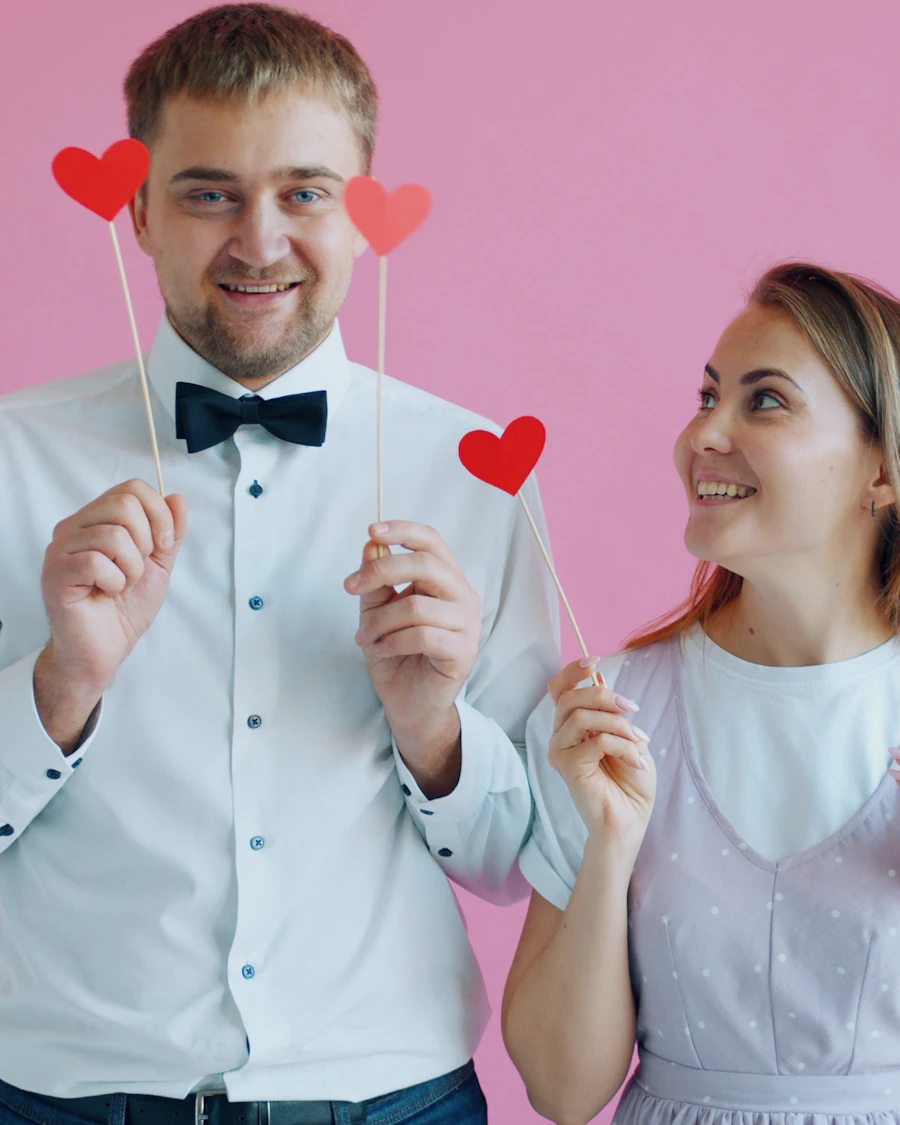 Couple posing with heart props against a pink backdrop
