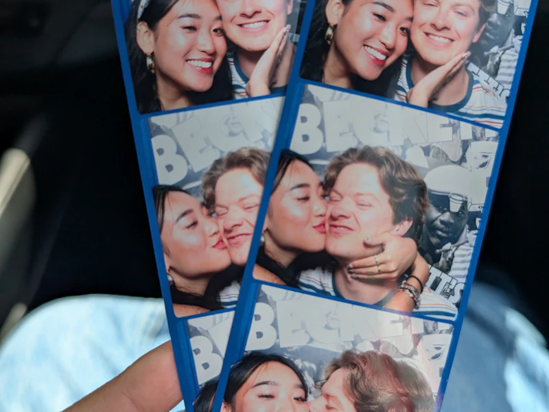 Hand holding two photo booth strips of a couple